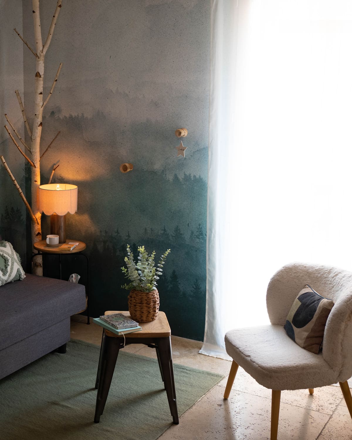 Coin détente du cabinet de Claix, lampe et fauteuil devant le papier peint forêt